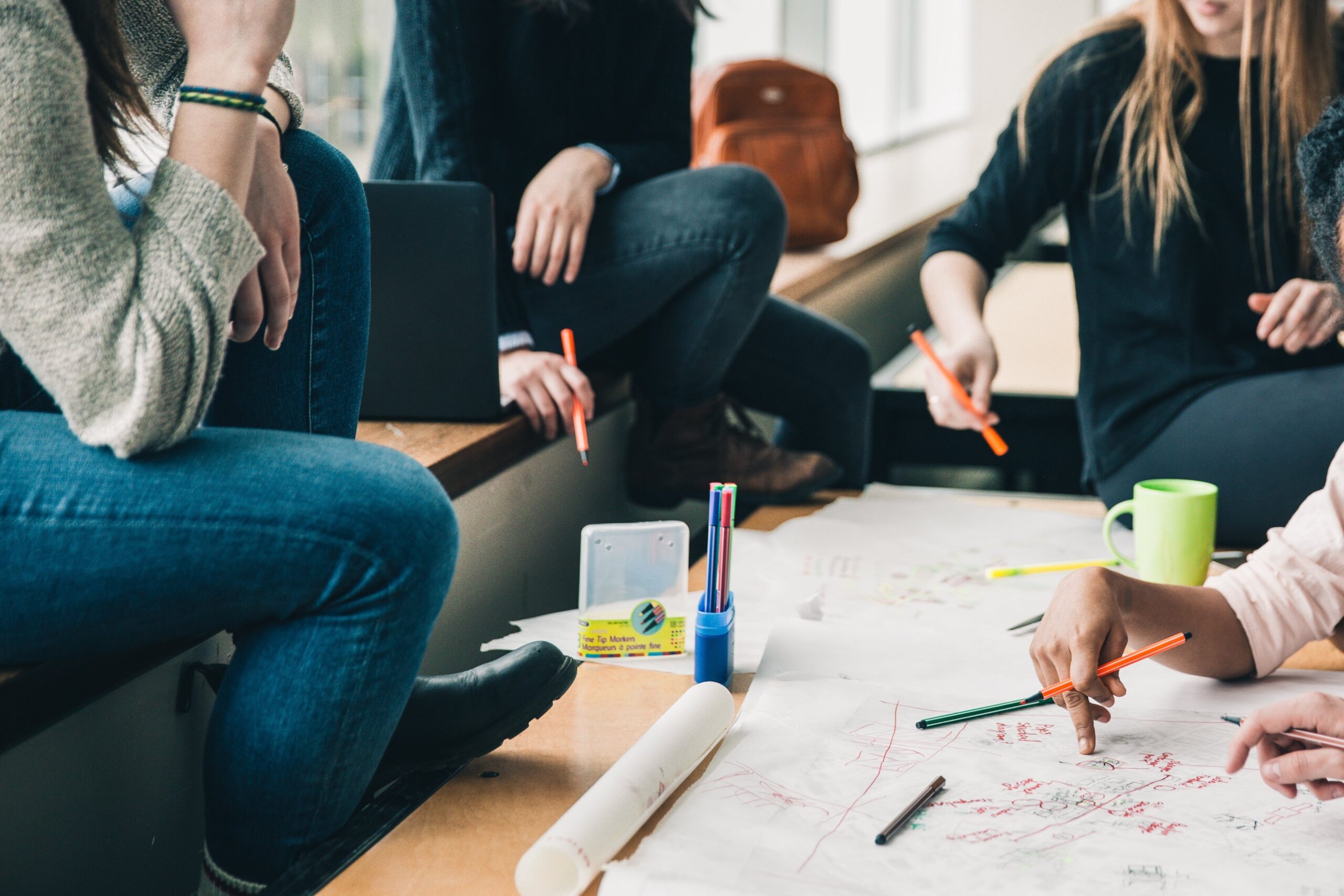 Gruppe von Menschen bei gemeinsamer Planung mit Stiften und Skizzen – symbolisch für Professionalisierung durch die Schulleitung im schulischen Kontext.